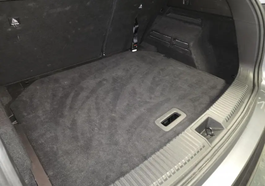 Coffre ouvert du Renault Austral gris, vue plongeante sur le faux plancher en tissu noir.