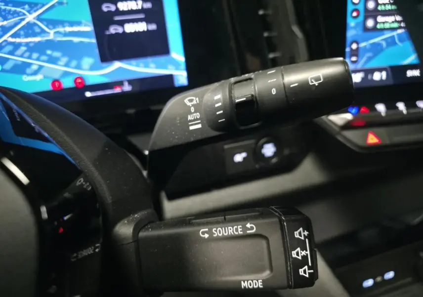 Gros plan sur les commandes au volant du Renault Austral gris, avec tableau de bord digital et écran multimédia en arrière-plan.