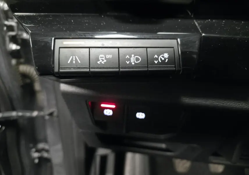 Gros plan sur les commandes noires du tableau de bord du Renault Austral 2024, avec voyants lumineux rouges et blancs.
