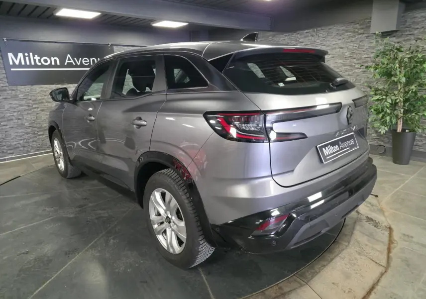Vue 3/4 arrière droite d'un Renault Austral gris schiste avec feux LED et calandre à damier dans un showroom.