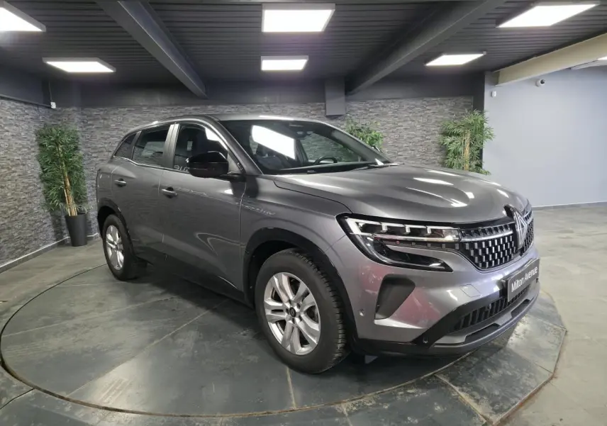 Renault Austral gris schiste en 3/4 avant droit, calandre damier ice black et feux LED Pure Vision visibles.