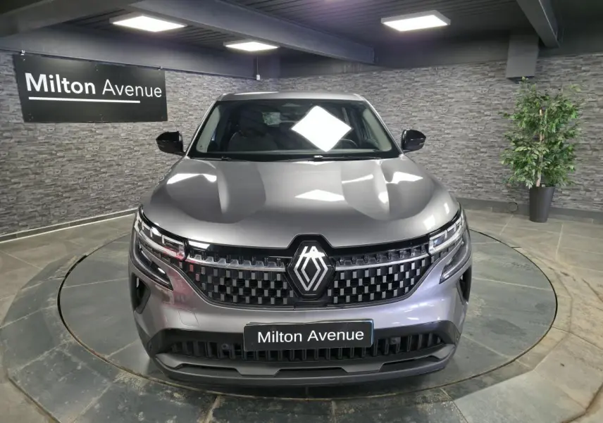 Renault Austral gris vu de face en intérieur, avec calandre damier ice black et logo central lumineux.