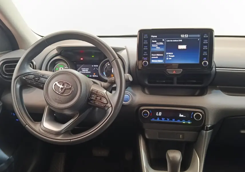 Vue intérieure centrée sur le volant cuir et l'écran tactile 8 pouces du tableau de bord de la Toyota Yaris hybride 2023.