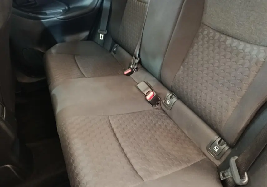 Vue latérale intérieure des sièges arrière gris foncé de la Toyota Yaris Hybride 116h Design 2023, avec ceintures de sécurité visibles.