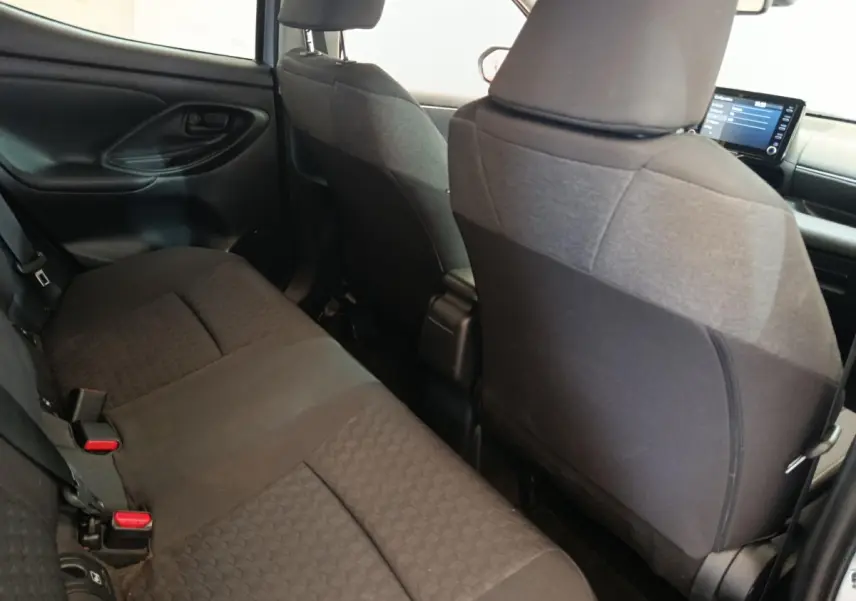 Vue intérieure arrière de la Toyota Yaris Hybride 116h Design 2023, sièges tissu noir et tableau de bord avec écran tactile.