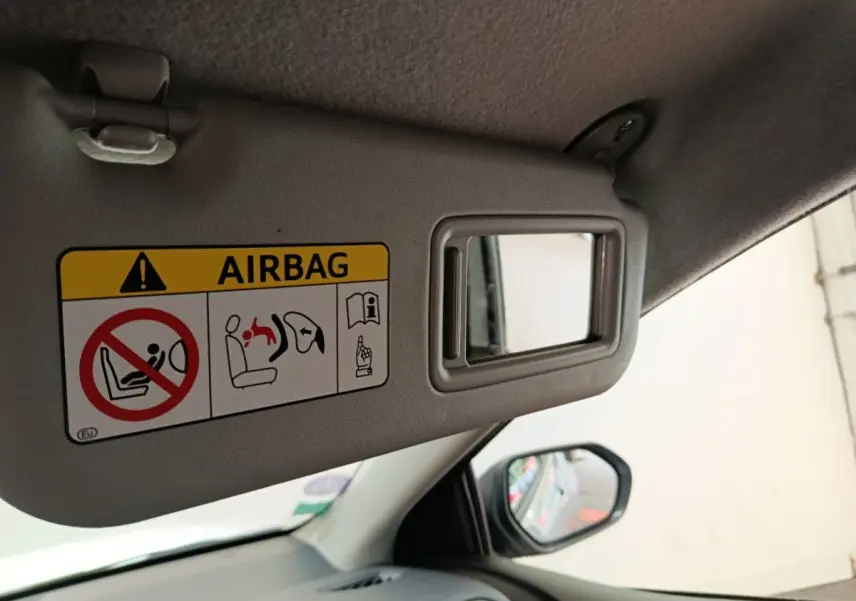 Détail du pare-soleil côté conducteur avec miroir de courtoisie et avertissement airbag dans une Toyota Yaris gris clair.