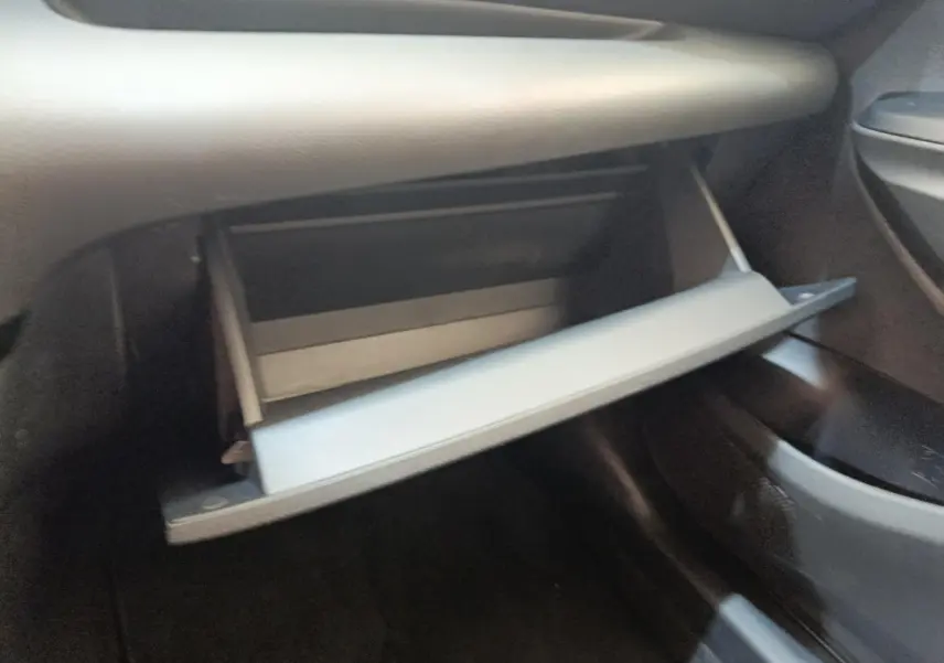 Gant de boîte à gants ouvert côté passager dans l'habitacle sombre d'une Toyota Yaris Hybride 116h Design 2023.