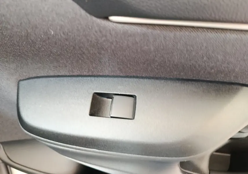 Détail du bouton de verrouillage centralisé sur la porte intérieure d'une Toyota Yaris hybride gris clair.