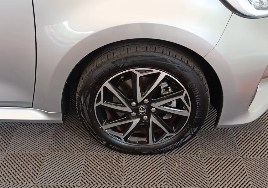 Gros plan sur la roue avant gauche de la Toyota Yaris hybride gris clair, avec jante alliage noire et argentée.