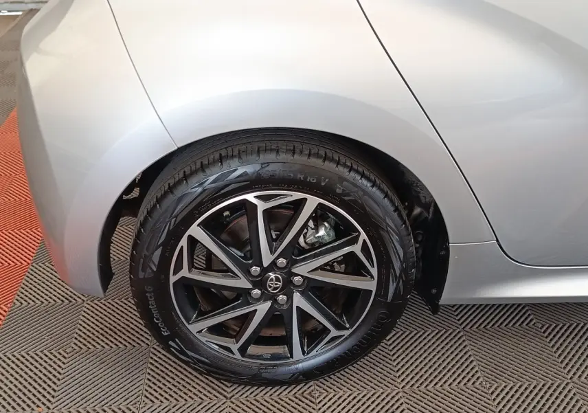 Gros plan sur la roue arrière droite de la Toyota Yaris hybride gris clair, avec jante alliage noire et argentée.