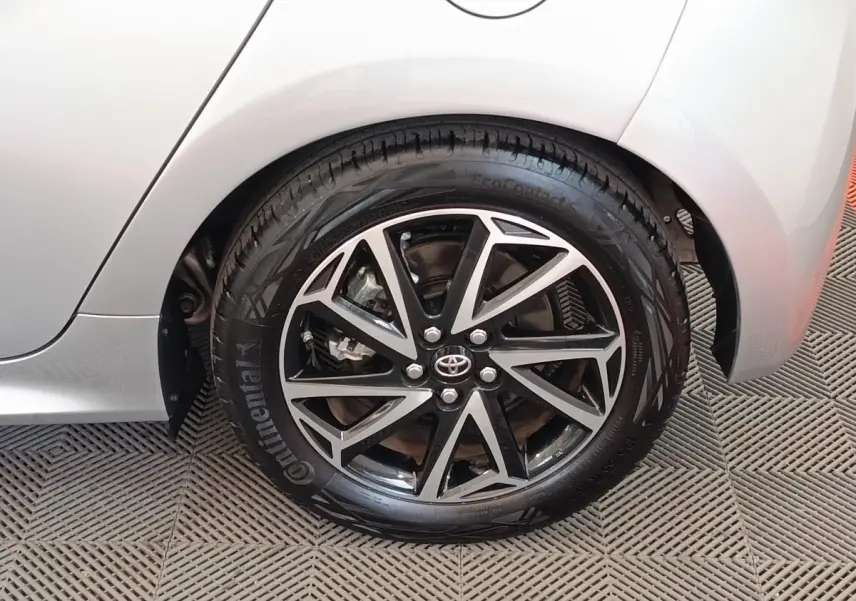 Gros plan sur la roue arrière droite gris clair de la Toyota Yaris Hybride 116h Design avec jante alliage noire et argent.