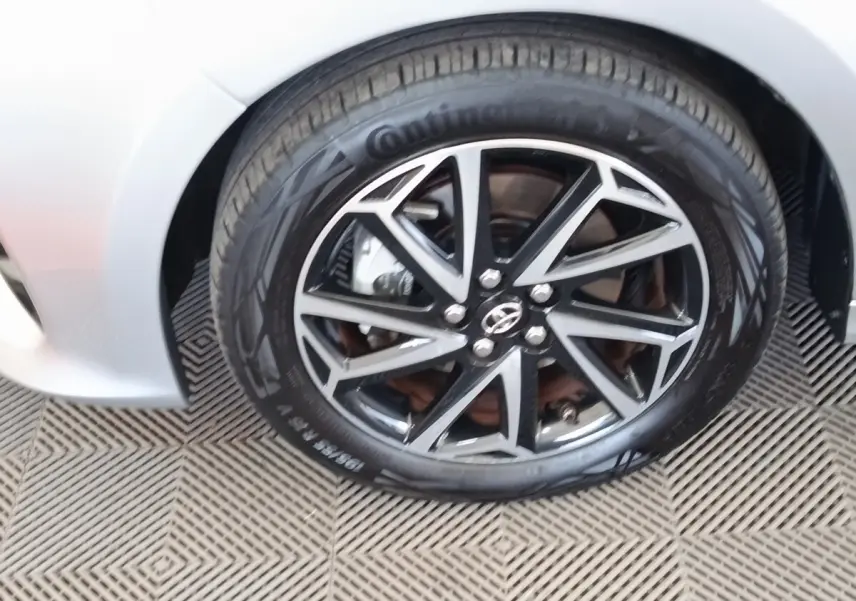Gros plan sur la roue avant droite de la Toyota Yaris hybride gris clair, avec jante alliage noire et argentée.