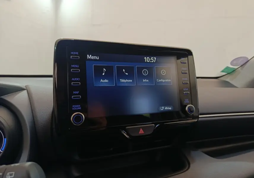 Écran tactile central allumé du tableau de bord d’une Toyota Yaris Hybride gris clair, vue intérieure frontale.