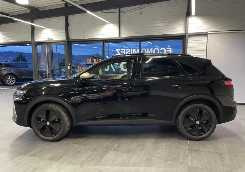 DS7 Crossback noir métallisé vu de profil côté gauche en intérieur avec jantes noires et coques de rétroviseurs dorées.