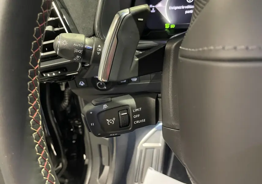 Gros plan sur la commande de régulateur de vitesse au volant cuir noir avec surpiqûres rouges du DS7 Crossback noir métallisé.