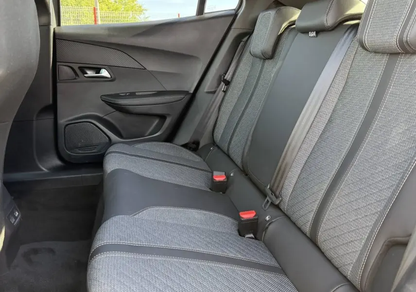 Vue latérale droite de la banquette arrière gris tissu et cuir du Peugeot e-2008 2025 avec ceintures et appuie-têtes.