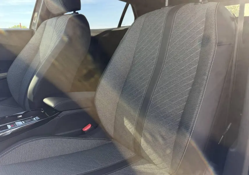 Gros plan sur les sièges avant en tissu gris Casual Lomsa embossé du Peugeot e-2008 2025, lumière naturelle traversante.