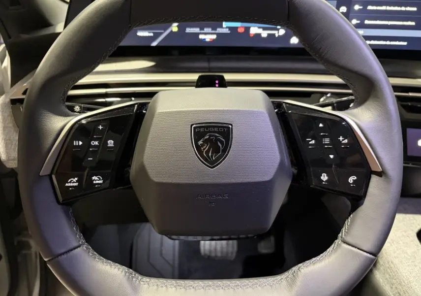 Volant cuir gris du Peugeot 3008 1.2 Hybrid 145 Allure, avec commandes multifonctions et logo lion central visible.