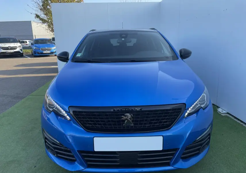 Vue frontale d'une Peugeot 308 SW 2 bleu Vertigo avec calandre noire et feux LED distinctifs.