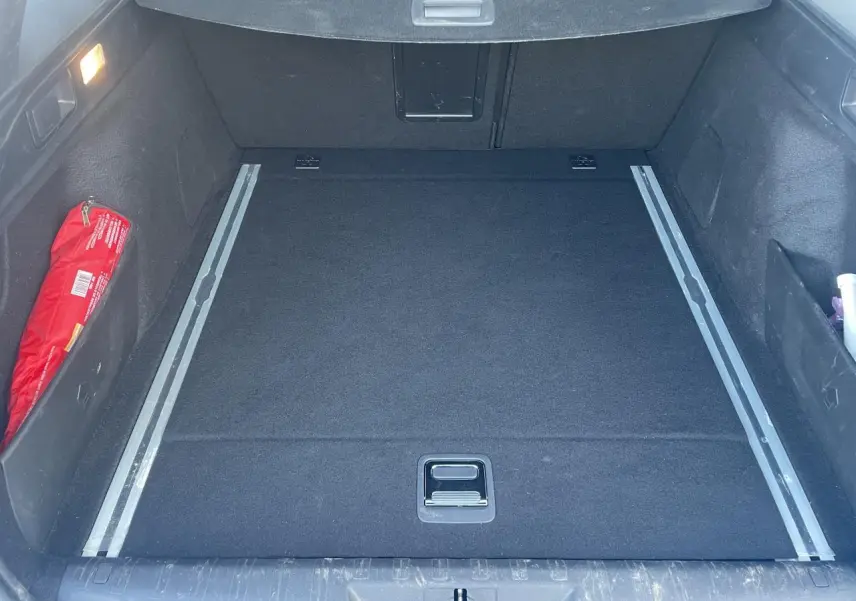 Coffre spacieux de Peugeot 308 SW 2 bleu Vertigo, vue intérieure avec rails de coffre et rangement latéral rouge.