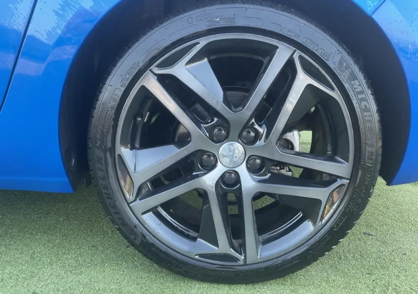 Gros plan sur la jante alliage 18 pouces diamantée noire et grise du côté gauche d'une Peugeot 308 SW bleu Vertigo.
