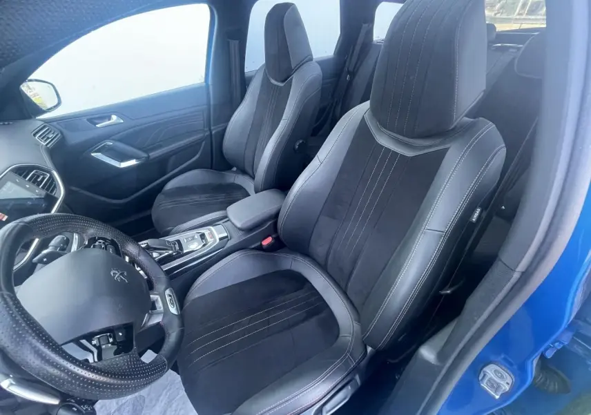 Vue intérieure côté conducteur d'une Peugeot 308 SW bleu Vertigo, sièges TEP et Alcantara noirs avec surpiqûres rouges.