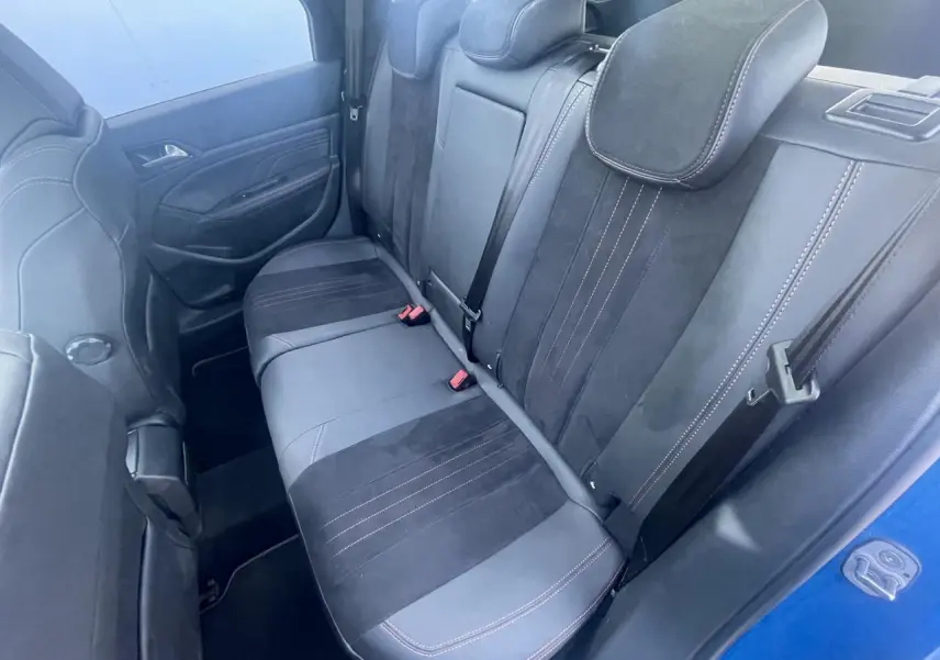 Vue intérieure côté arrière gauche montrant la banquette arrière noire avec surpiqûres rouges d'une Peugeot 308 SW Bleu Vertigo.