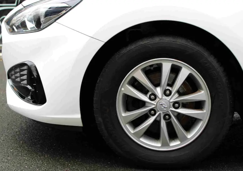 Gros plan sur la roue avant droite et le pare-chocs blanc polaire d'une Hyundai i30 SW 2022 avec jante alliage.