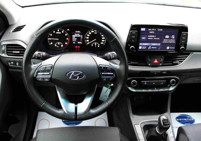 Vue intérieure centrée sur le volant et le tableau de bord de la Hyundai i30 SW 2022 avec boîte manuelle.