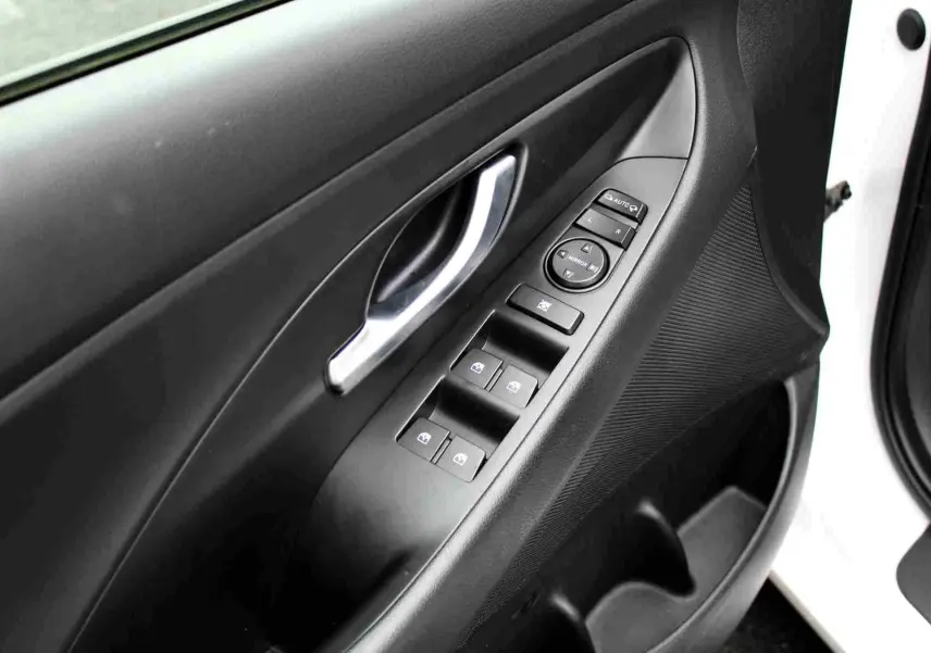 Gros plan sur la porte avant gauche d'une Hyundai i30 SW blanche avec commandes électriques des vitres et rétroviseurs.