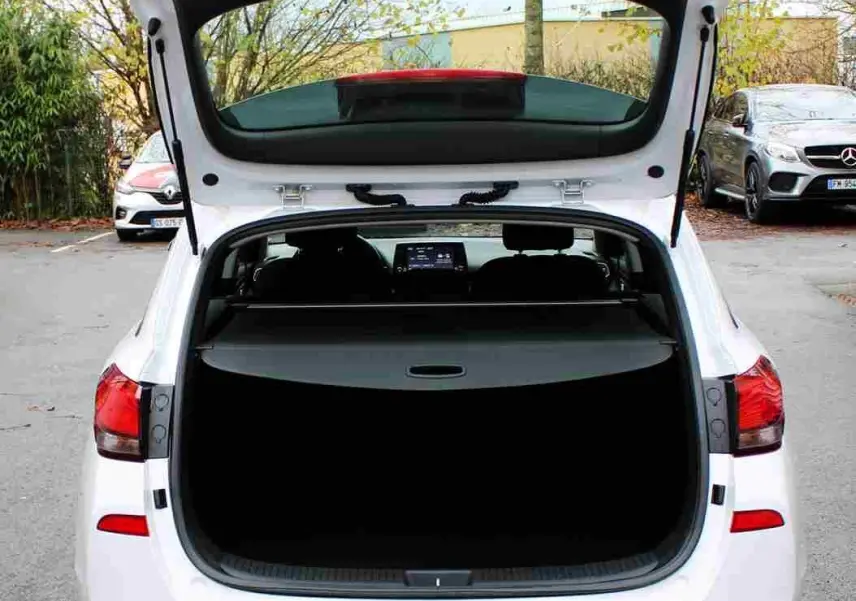 Vue arrière d'une Hyundai i30 SW blanche polaire 2022 avec coffre ouvert et intérieur visible.