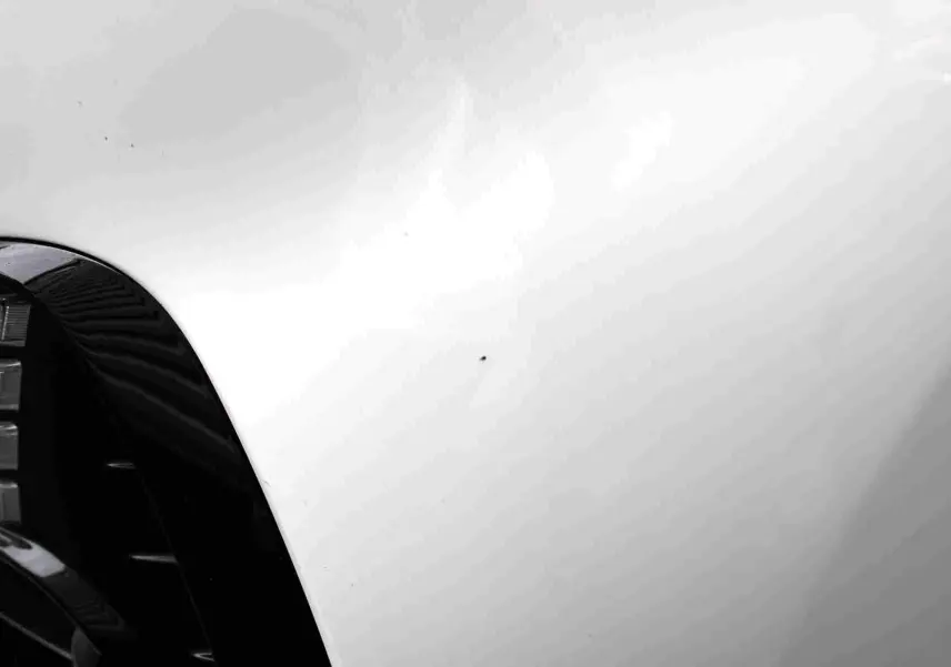 Vue rapprochée du capot blanc polaire d'une Hyundai i30 SW 2022 avec reflet flou d'une silhouette.