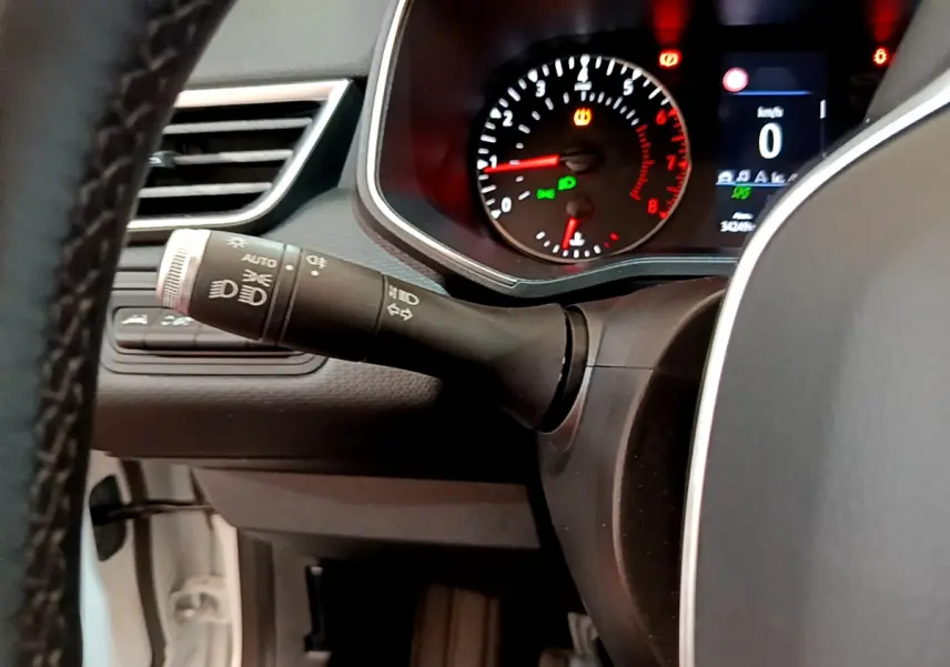 Gros plan sur le commodo gauche et le tableau de bord allumé de la Renault Clio Business TCe 100 blanche de 2020.