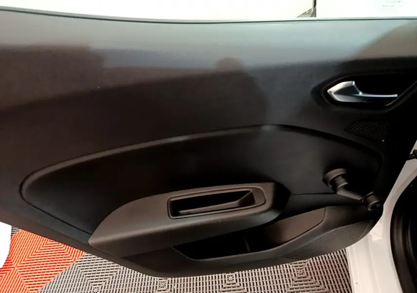 Vue rapprochée de la porte intérieure côté droit de la Renault Clio Business TCe 100 blanche, avec poignée et manivelle de vitre.