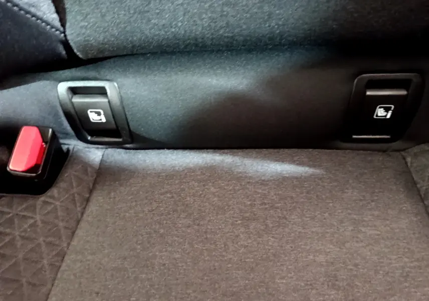 Gros plan sur la banquette arrière noire de la Renault Clio Business TCe 100, montrant les commandes de rabattement des sièges.