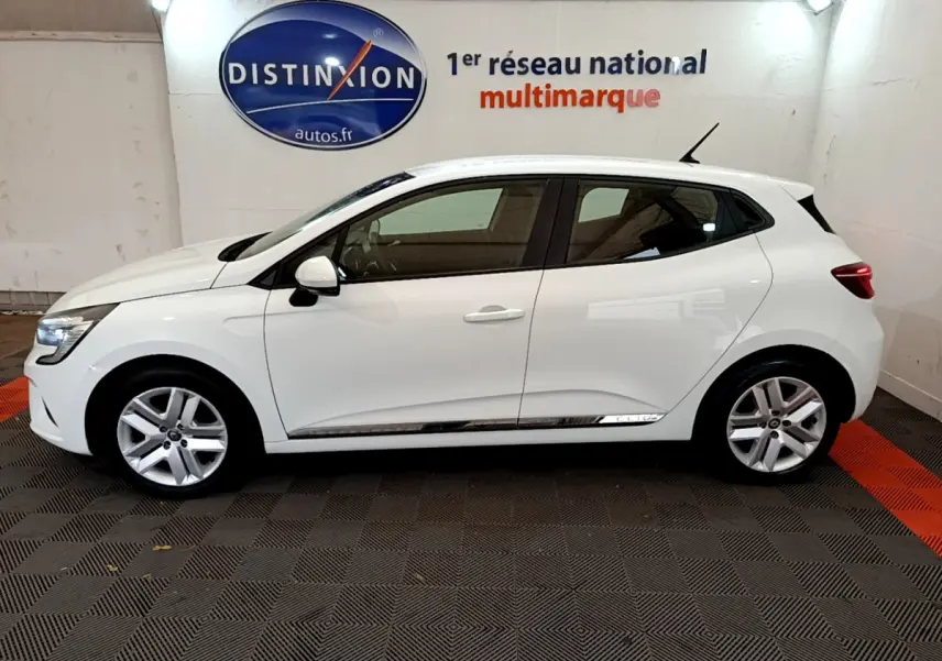 Profil côté gauche d'une Renault Clio Business TCe 100 blanche, garée en intérieur avec jantes alliage et vitres teintées.