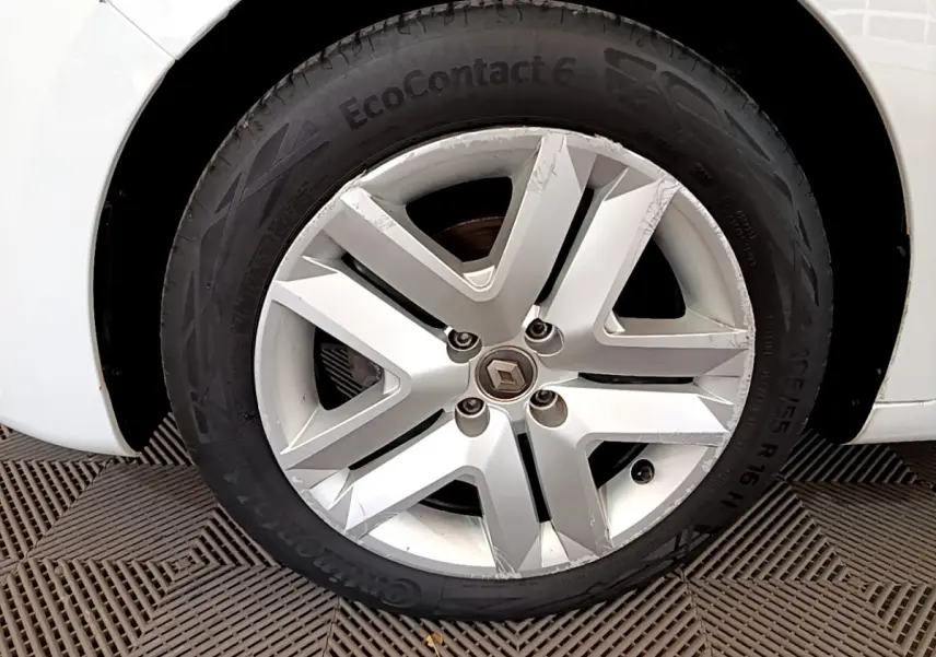 Gros plan sur la roue avant droite blanche d'une Renault Clio Business TCe 100 avec jante alliage griffée.