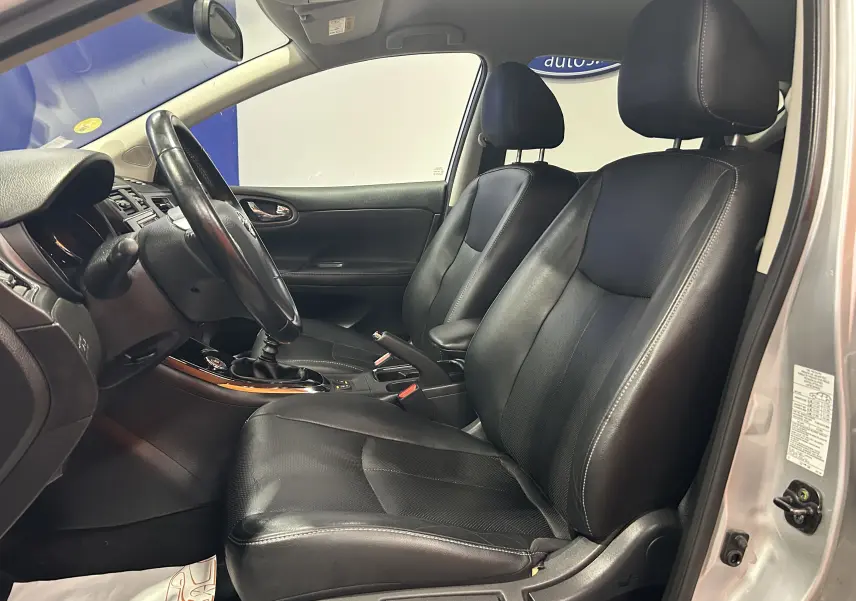 Vue intérieure côté gauche montrant les sièges avant en cuir noir et la boîte manuelle d'une Nissan Pulsar gris 2018.