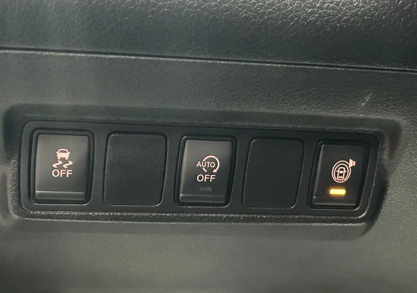 Gros plan sur les boutons de commande noirs du tableau de bord intérieur d’une Nissan Pulsar gris 2018.