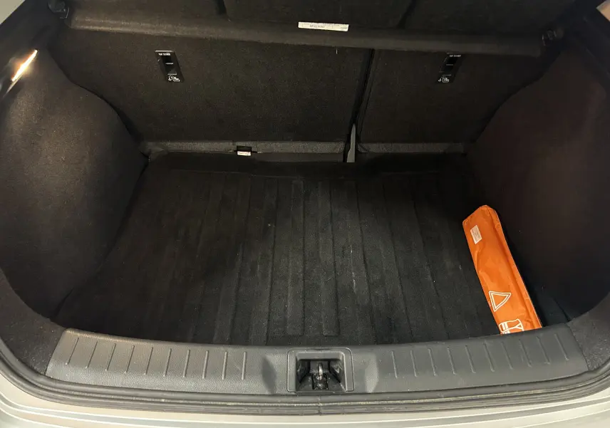 Coffre ouvert de la Nissan Pulsar gris, montrant un espace de rangement propre avec un triangle de signalisation orange sur la droite.