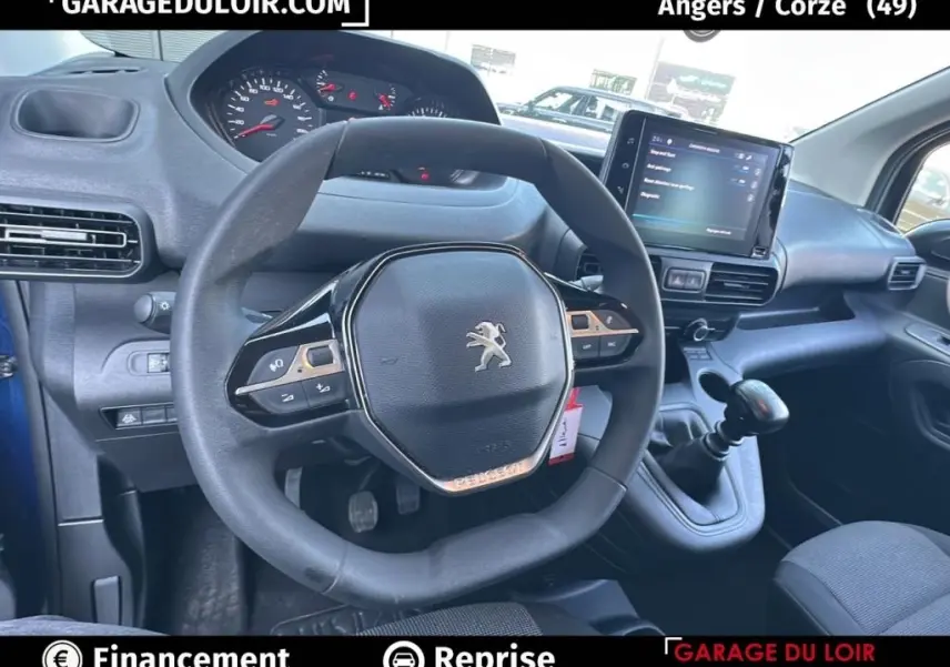 Vue intérieure centrée sur le volant Peugeot d'un Rifter bleu 2024 avec tableau de bord et écran tactile visible.