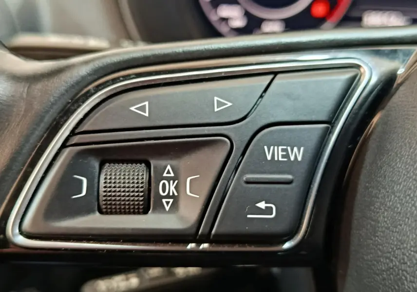Gros plan sur les commandes multifonctions en plastique noir du volant d’un Audi Q2 35 TFSI gris foncé, 2022.