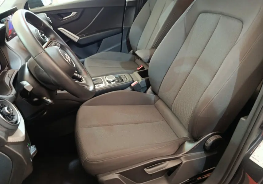 Vue intérieure côté conducteur de l'Audi Q2 35 TFSI 150 S Tronic Business Line 2022 avec sièges tissu gris et volant cuir.