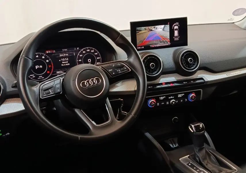 Vue intérieure de l'Audi Q2 35 TFSI 2022 montrant le volant cuir, tableau de bord digital et écran tactile central.