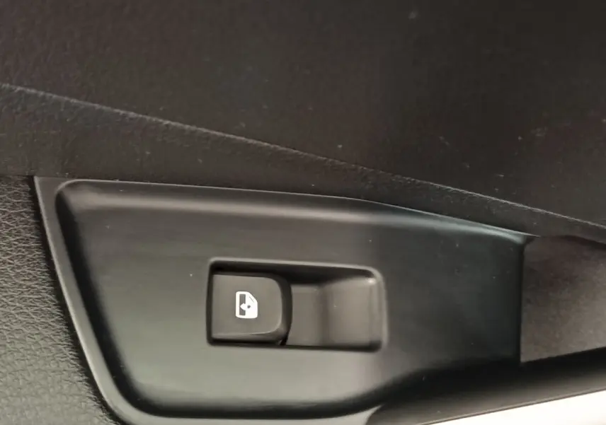 Bouton de commande de lève-vitre électrique sur panneau de porte intérieur noir, détail d'Audi Q2 2022.