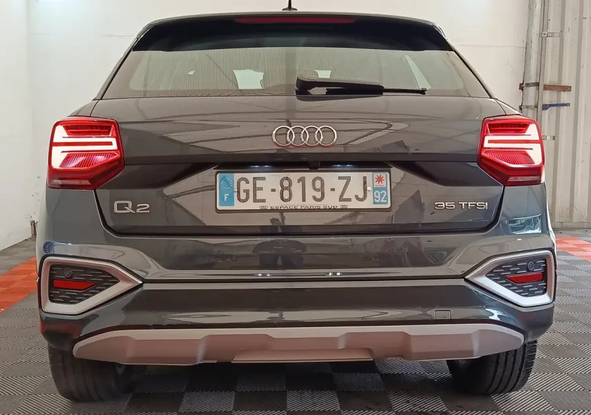 Vue arrière d’un Audi Q2 gris foncé 35 TFSI 150 S Tronic avec feux LED et logo distinctif au centre.