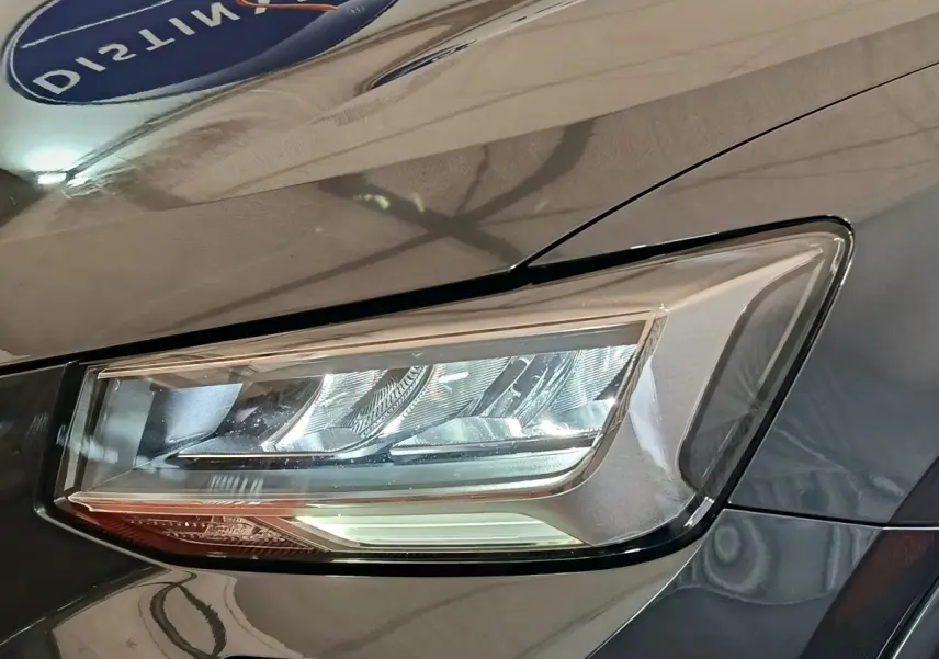 Gros plan sur le phare avant droit d’un Audi Q2 gris foncé, mettant en valeur son design LED moderne.