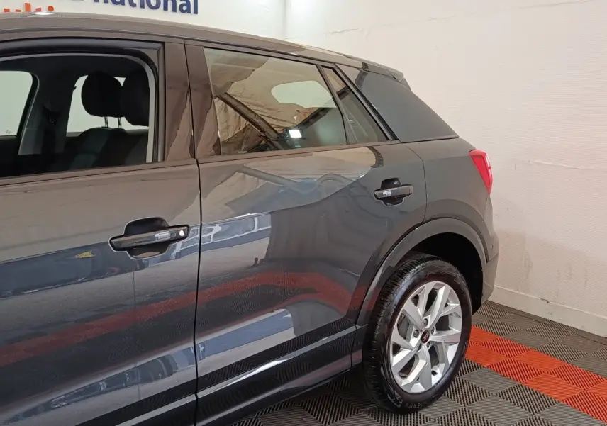 Vue côté droit arrière d'un Audi Q2 gris foncé avec jantes alliage et poignées de porte noires.