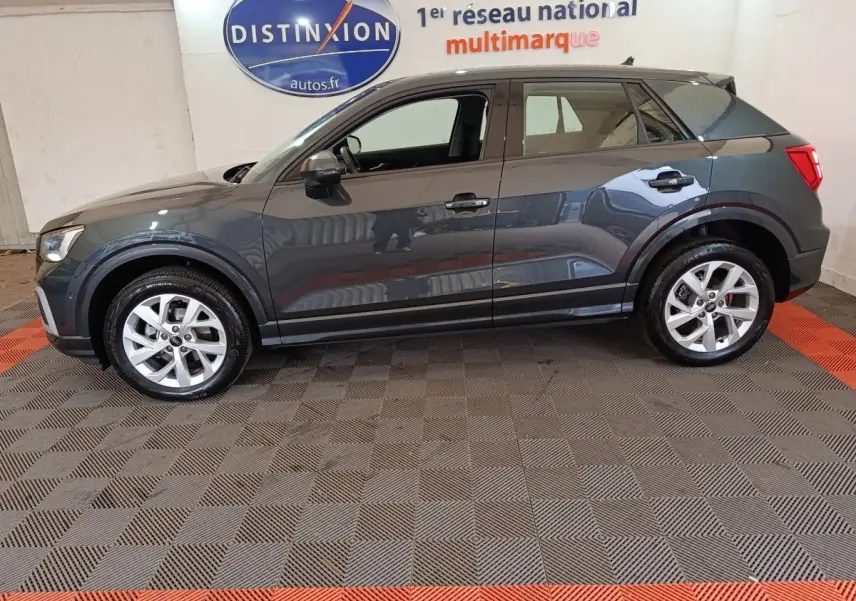 Audi Q2 gris foncé vue de profil côté gauche, avec jantes argentées et rétroviseurs assortis.