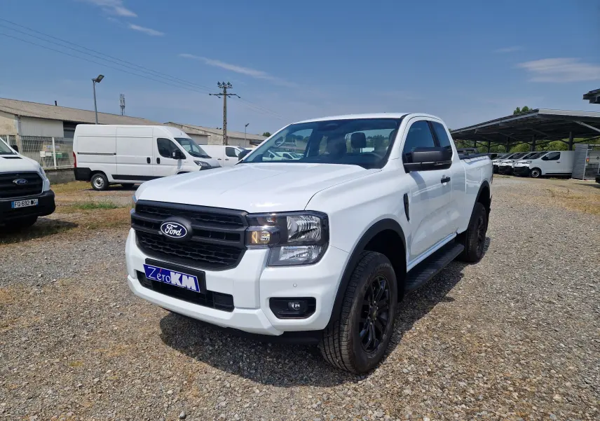 Ford Ranger Super Cabine blanc vu en 3/4 avant droit, avec calandre noire et marchepieds latéraux noirs.